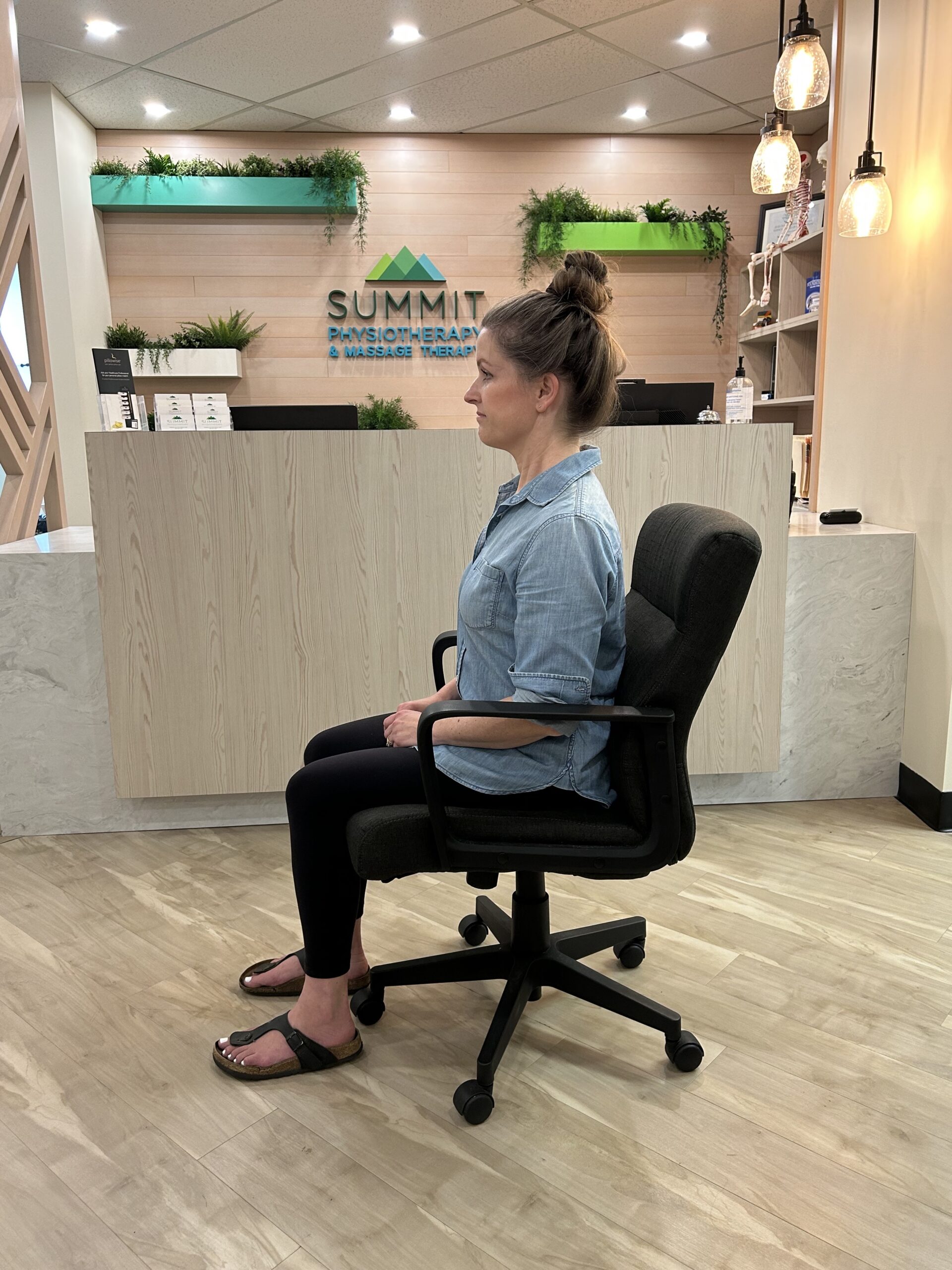 A lady sitting in a office chair demonstrating proper sitting posture.