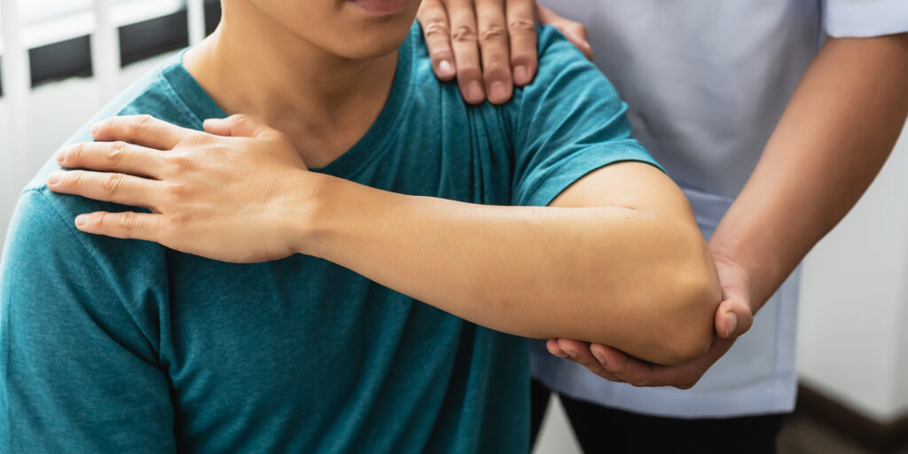 Close-up of a physiotherapist assisting a patient with a shoulder stretch.